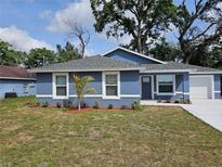Charming blue home features a well-manicured front yard with a lovely garden and a fresh concrete driveway at 1121 W 9Th St, Lakeland, FL 33805