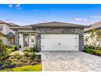 Charming single-Gathering home with a stone-accented facade and a brick paver driveway leading to a two-car garage at 7661 Somersworth Dr, Kissimmee, FL 34747