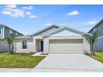 Charming single-story home with a two-car garage, manicured lawn, and lush landscaping at 1050 Foreshore Ln, Haines City, FL 33844
