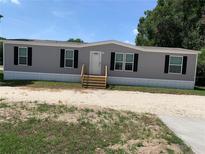Charming single-story home with gray siding, black shutters, and a well-maintained gravel driveway at 9494 Se 144Th Pl, Summerfield, FL 34491