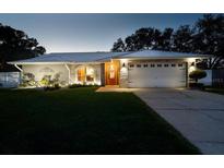 Charming single-story home with manicured lawn, stone accents, and well-lit driveway at dusk at 3610 Amber Ln, Lakeland, FL 33812