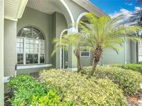 Inviting front entrance featuring arched doorways, large windows, and lush landscaping at 2806 Spinning Silk Ct, Kissimmee, FL 34747