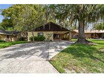 Charming single-story home featuring a spacious driveway and a covered carport area, surrounded by mature trees at 519 Market W Sq, Lakeland, FL 33813