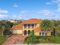 Stunning two-story home with a red tile roof, lush landscaping, and a paver driveway at 1140 Terralago Way, Kissimmee, FL 34746