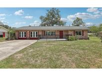 Charming brick home with a well-maintained lawn, red accents and black metal fence at 1212 Blake Ave, Auburndale, FL 33823