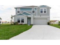 Two-story home with gray and blue siding, white trim, and a two-car garage, set on a green lawn at 1424 Axel Cir, Winter Haven, FL 33880