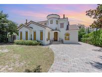 Charming two-story home featuring stucco siding, a tile roof, arched windows, and a brick driveway at 952 Moss Ln, Winter Park, FL 32789
