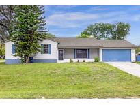 Charming single-story home with a blue garage door and shuttered windows, surrounded by a lush green lawn at 3331 Lime Tree Dr, Edgewater, FL 32141