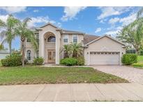 Stunning two-story home featuring a stucco facade, arched entry, and lush landscaping at 239 Beacon Pointe Dr, Ocoee, FL 34761