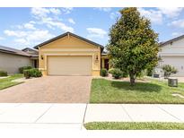 Charming single-Gathering home with a two-car garage, brick driveway, and beautiful landscaping at 472 Pontevedra Rd, Davenport, FL 33837