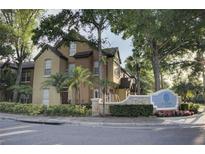 Beautiful townhome with lush landscaping in a well-maintained community, featuring mature trees and a stone entrance sign at 6300 Raleigh St # 102, Orlando, FL 32835