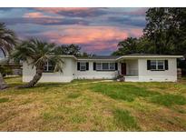 Charming single-story home with a well-maintained lawn and palm trees, under a beautiful colorful sky at 1816 W Lake Parker Dr, Lakeland, FL 33805