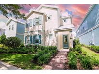 Charming two-story home with teal shutters, landscaped yard, and a welcoming brick pathway to the front door at 1430 Reunion Blvd, Reunion, FL 34747