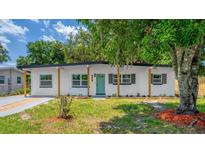 Charming single-story home featuring a well-maintained lawn, a vibrant teal door, and a covered front porch with wood pillars at 4116 Winona Dr, Orlando, FL 32812