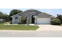 Charming single-story home with well-manicured lawn, gray exterior, and attached two-car garage at 938 Oxford Way, Lake Wales, FL 33853