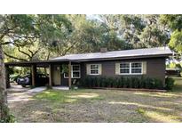 Charming single-story home with brown exterior, covered carport, well maintained landscaping, and a metal roof at 2748 Cr 543, Sumterville, FL 33585