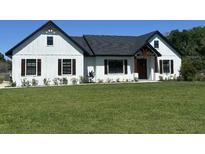 Charming modern farmhouse with white siding, dark trim, and a well-manicured lawn at 112 Cr 532B, Bushnell, FL 33513