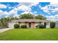 Charming single-story home with a well-maintained lawn, brick accents, and a beautiful green front door at 1511 Avenue F Ne, Winter Haven, FL 33881