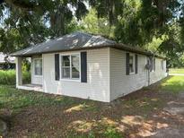 Cozy single story home with white siding and a metal roof surrounded by mature trees at 408 S Orange Ave, Fort Meade, FL 33841