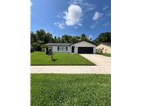 Charming single-story home with a well-manicured lawn and a modern black garage door at 34 Aaron Cir, Ormond Beach, FL 32174