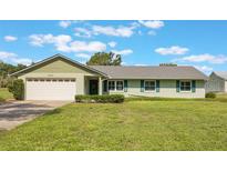 Charming single-story home featuring a well-maintained lawn, attached garage, and complementary green shutters at 21551 Lake Seneca Rd, Eustis, FL 32736