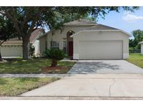 Inviting single-story home with a well-manicured lawn, two-car garage, and a red front door at 1416 Silverthorn Dr, Orlando, FL 32825
