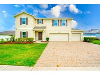 Charming two-story home featuring a brick driveway, a well-maintained lawn and beautiful landscaping at 383 Blue Lake Cir, Kissimmee, FL 34758