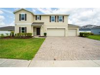 Charming two-story home boasts a paver driveway and a three-car garage at 383 Blue Lake Cir, Kissimmee, FL 34758