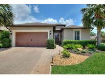 Inviting home with a well-manicured lawn, tropical landscaping, and a paver driveway that leads to a two-car garage at 224 Granada Ln, Davenport, FL 33837