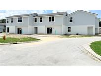 New two-story townhomes boast light gray siding and a white base with well-lit windows at 222 Carpenters Way # 71, Lakeland, FL 33805