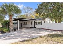 Charming home featuring a side carport and white exterior with dark trim, surrounded by lush landscaping at 2800 E Anderson St, Orlando, FL 32803