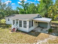 Charming single-story home with a carport, a screened-in porch, and mature trees at 28712 Azalea Ave, Paisley, FL 32767