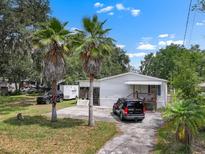 Charming single-story home with a cozy front porch, palm trees, and a spacious driveway at 2912 Fletcher Ave, Lakeland, FL 33803