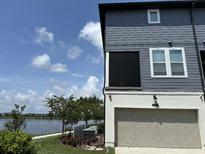 Two-story townhome featuring a two-car garage, lake view, and a well-maintained lawn at 12684 Willstatter Ave, Orlando, FL 32827