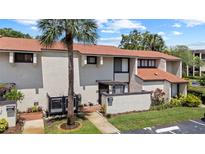 Inviting townhouse featuring a well-manicured lawn, mature palm tree, and neutral-toned exterior at 4160 Player Cir # 109, Orlando, FL 32808