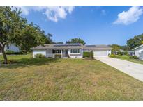 Charming single-story home featuring a well-manicured lawn, solar panels, and an attached two-car garage at 8225 Sw 108Th Street Rd, Ocala, FL 34481