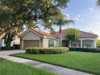 Charming single-story home with a red tile roof, a well-manicured lawn, and mature landscaping at 12064 Navale Ln, Orlando, FL 32827
