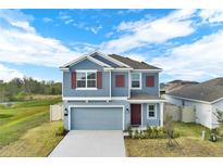 Charming two-story home with a well-maintained lawn, gray siding, and red shutters under a bright, partly cloudy sky at 271 Inman Blvd, Winter Haven, FL 33881