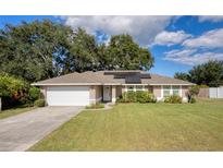 Charming one-story home featuring a well-manicured lawn, two-car garage, and solar panels at 4462 Iris S St, Lakeland, FL 33813