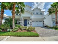Charming two-story home featuring a well-manicured lawn, colorful landscaping, and a two-car garage at 1423 Bunker Dr, Davenport, FL 33896