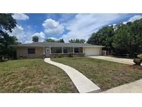 Charming single-story home with a long driveway, lush lawn and covered porch at 3115 Lake Arnold Pl, Orlando, FL 32806