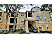 Inviting two-story condo building painted in yellow and cream tones, featuring stairs to the residences above at 2572 Robert Trent Jones Dr # 1235, Orlando, FL 32835