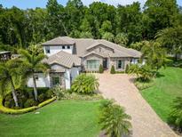 Stunning aerial view of a luxury home with a paver driveway, lush landscaping, and a tile roof surrounded by mature trees at 2242 Soaring Eagle Pl, Lake Mary, FL 32746