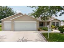 Charming single-story home featuring a two-car garage, well-maintained landscaping, and a welcoming facade at 310 Knoll Pl, The Villages, FL 32162