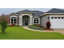Charming single-story home featuring stone accents, a two-car garage, and beautifully landscaped front yard at 7144 Remington Oaks Loop, Lakeland, FL 33810