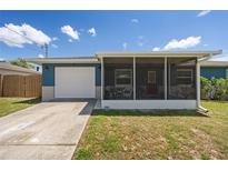 Charming home with a blue exterior, white garage door, and screened front porch with ample greenery at 3983 Shay Dr, Bartow, FL 33830