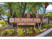 Exterior sign for One Thousand Oaks Condominiums, surrounded by lush landscaping and mature palm trees at 1038 E Michigan St # 1, Orlando, FL 32806