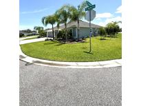 Well-maintained front yard with lush green grass and mature palm trees on a corner lot at 2613 Drew Cir, The Villages, FL 32163