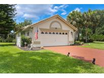 Inviting single-story home with a two-car garage, brick driveway, and well-manicured lawn at 414 Long Cove Ct, Ormond Beach, FL 32174