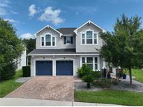 Charming two-story home featuring a brick driveway, blue garage doors and manicured landscaping at 5095 Southlawn Ave, Orlando, FL 32811